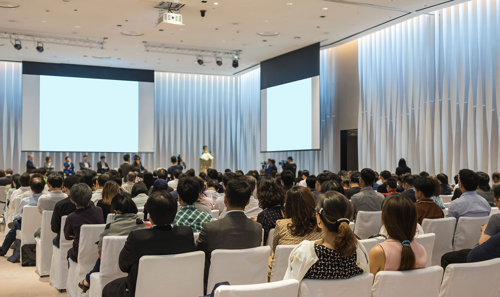 Fest verbauter Beamer und ausfahrbahre Leinwände in einem Veranstaltungssaal