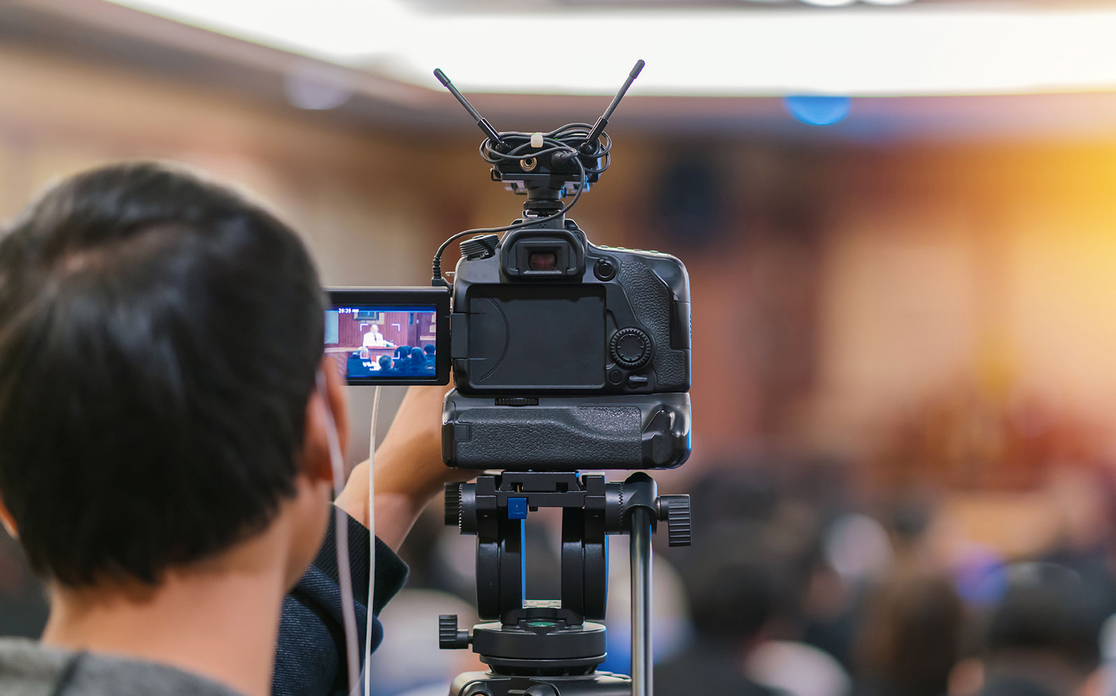 Veranstaltungstechniker steht vor einer Kamera, die einen Livestream der Veranstaltung überträgt