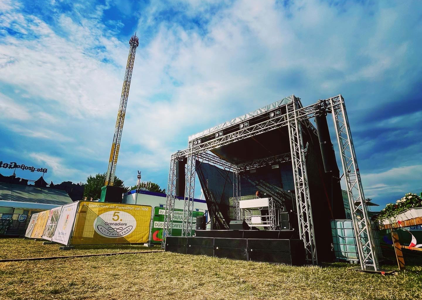 Open-Air-Festivalbühne mit großem Traversengerüst und DJ-Pult, aufgebaut auf einer Wiese